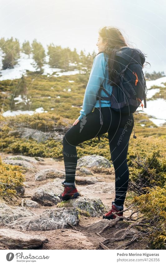 woman hiker standing in the mountain with sunlight. travel snowy landscape nature copy space female top freedom adventure hiking backpack peak rock cliff sky