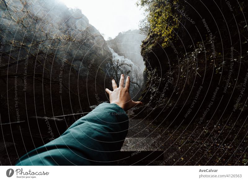 Inspirational shot of a hand in front of a waterfall on moody tones with copy space person power wilderness arms carefree enjoyment flow flowing freedom hipster