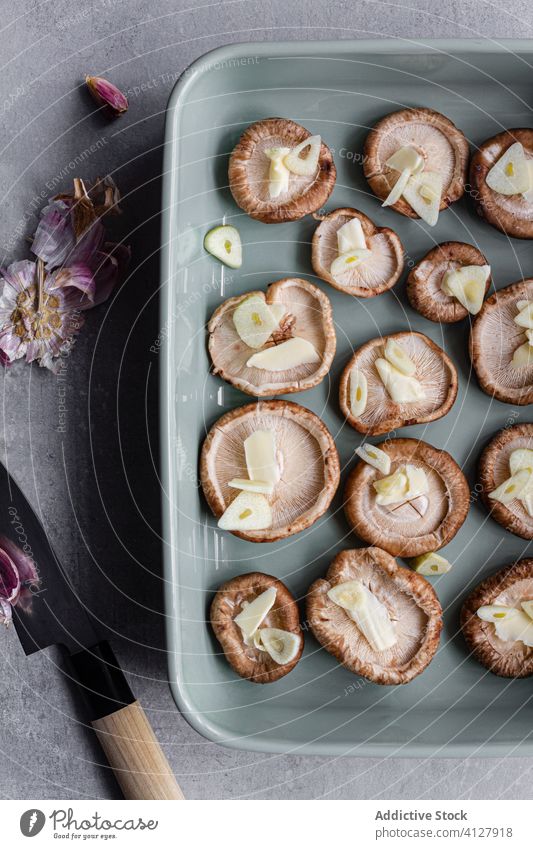 Fresh mushrooms with chopped garlic on ceramic tray food knife dish raw cooking meal fresh shiitake tasty uncooked cap homemade prepare recipe gastronomy