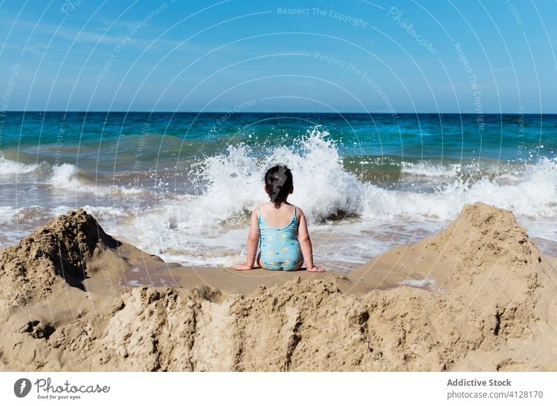 Little kid enjoying sea waves on beach sand summer girl water ocean travel coast little vacation holiday child shore resort rest carefree nature happy sit