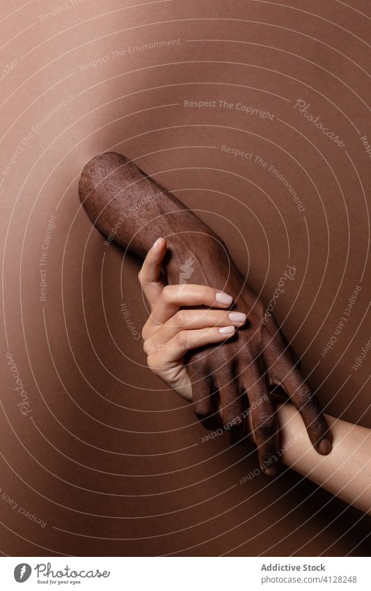 Unrecognizable crop multiracial couple holding hands behind paper curtain close people relax sensual embrace partner friend enjoy holiday fun friendship gentle