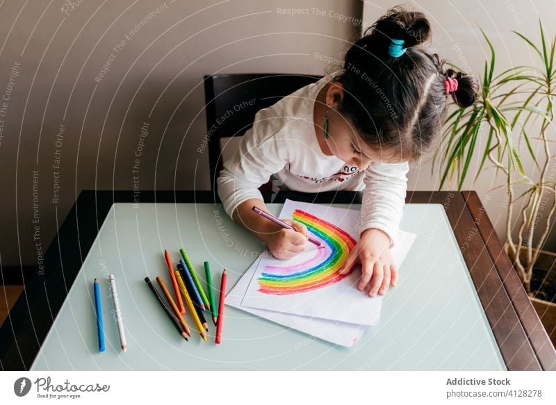 Girl drawing picture on paper at table at home girl rainbow pencil creative optimist positive colorful bright inspiration kid art child paint imagination