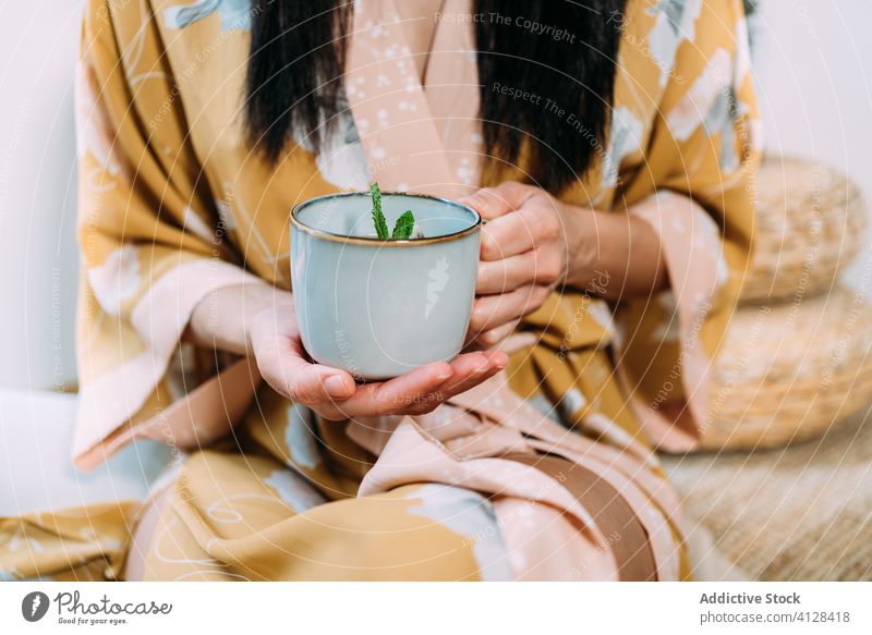 Young lady holding up mint tea at home woman relax drink hot beverage mug enjoy morning fresh delicious warm comfort casual female brunette calm cup rest brew