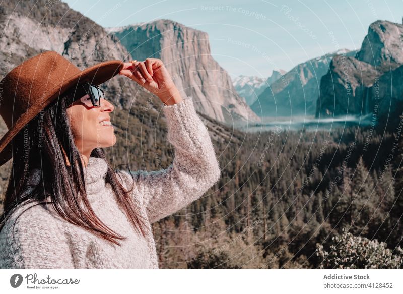 Happy woman enjoying sunny day in mountains travel happy relax forest yosemite park cliff edge sit rock stone national female style trendy landscape young