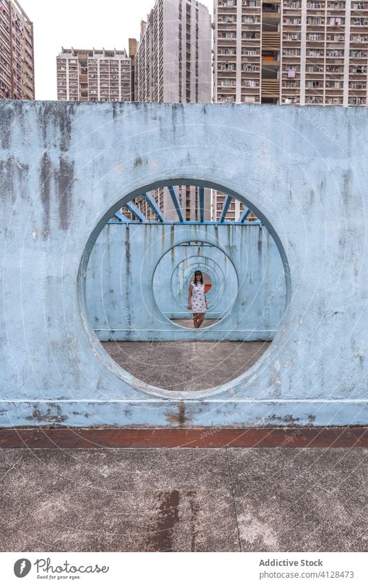 Woman near walls with tunnel in Hong Kong woman passage street installation city unusual creative summer female shek kip mei hong kong round shape outfit dress