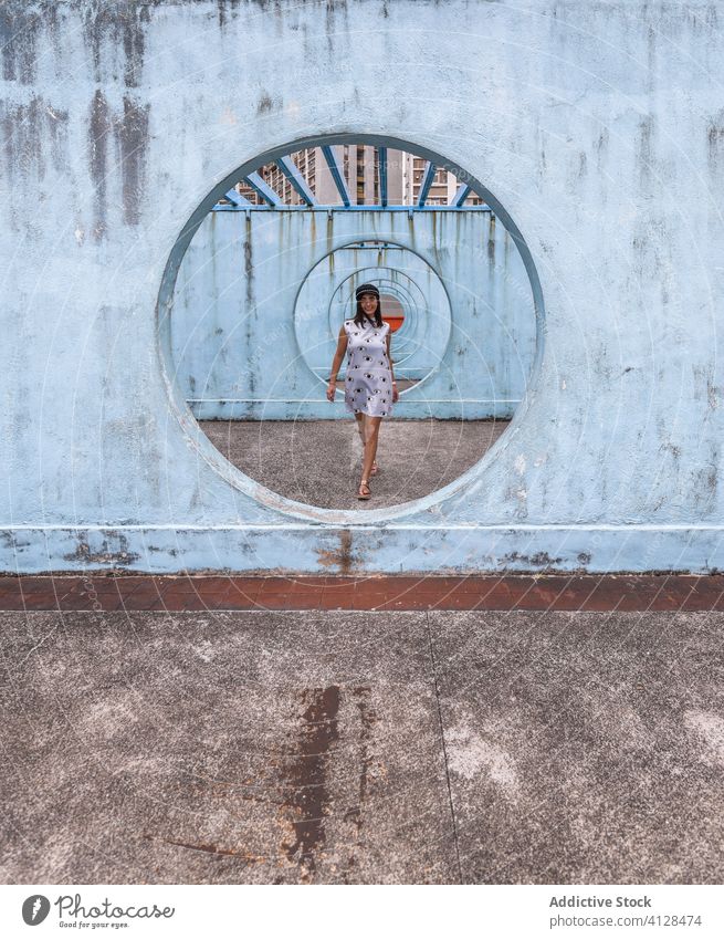 Woman near walls with tunnel in Hong Kong woman passage walking street installation city unusual creative summer female shek kip mei hong kong round shape