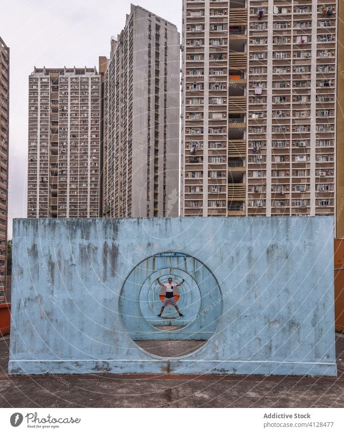 Cheerful man standing on walls with tunnel in Hong Kong street condominium courtyard cheerful city building apartment male shek kip mei hong kong installation