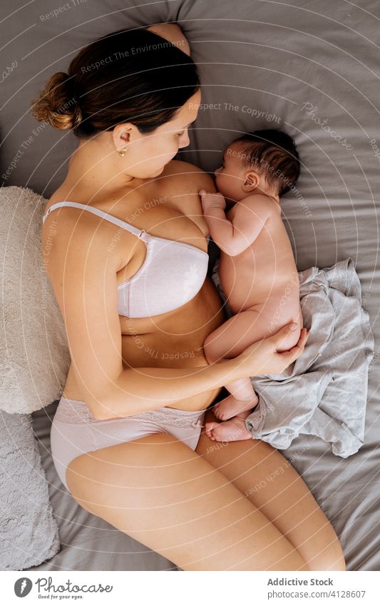 Mother breastfeeding little baby on bed woman mother love care home comfort cozy child underwear lingerie peaceful lying together cute young motherhood