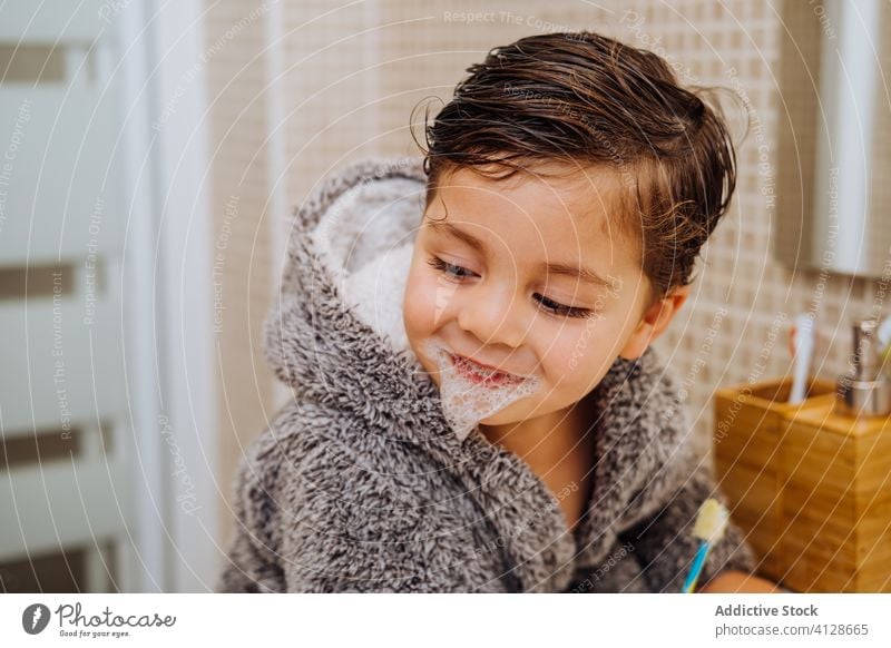 Little boy brushing teeth in bathroom toothbrush little child smile bathrobe kid oral hygiene wet hair cheerful soft cozy comfort cute home content delight