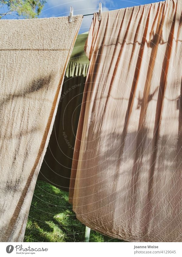 Dresses and towel hanging on a clothesline on a sunny afternoon. Grass and sky. Clothesline Washing day Laundry Household Clothes peg Housekeeping Dry Clean