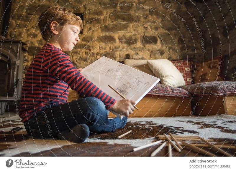 Kid drawing with colored pencils in sketchbook in living room boy house country cabin inspiration nature young carpet spain cantabria stone creative leisure