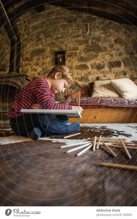 Kid drawing with colored pencils in sketchbook in living room boy house country cabin inspiration nature young carpet spain cantabria stone creative leisure