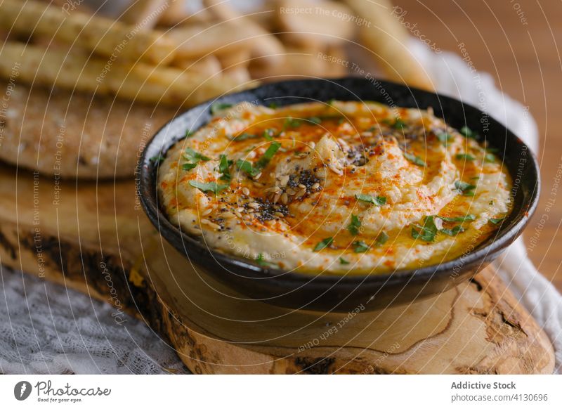 Homemade hummus on a wood table appetizer bowl bread chickpea creamy dip food healthy homemade Hummus lunch olive oil paprika parsley snack tahini tasty vegan