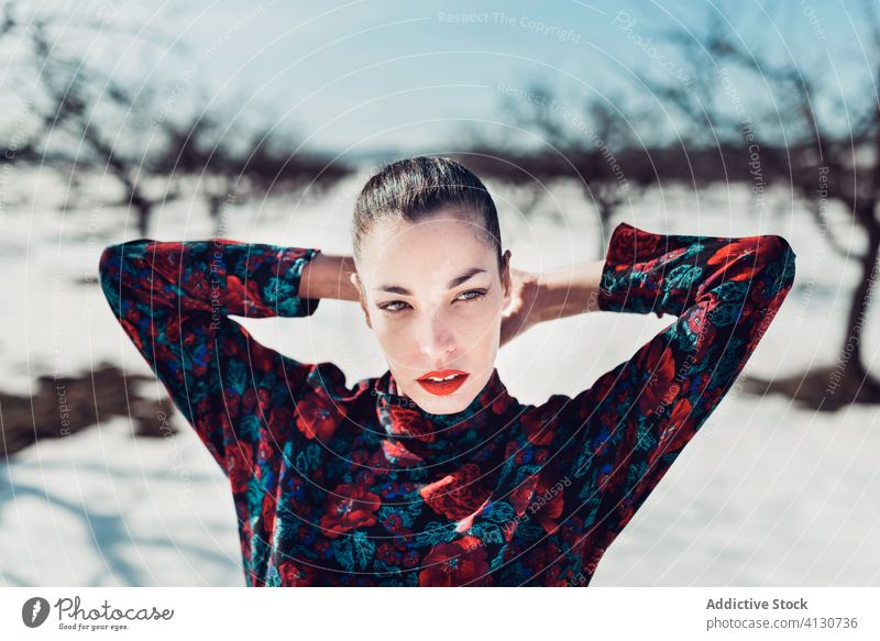 Confident trendy woman standing in snowy field style confident nature attractive modern fashion female charming serious colorful defiant red young sensual