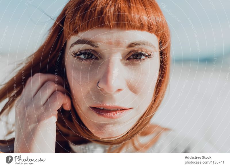 Sensual woman with red hair standing in snow field style trendy sensual redhead young nature attractive female ginger fashion modern charming elegant makeup