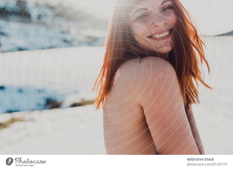 Young woman with red hair standing in snowy field topless winter flying hair nature happy relax wind female bare shoulders valley enjoy naked long hair