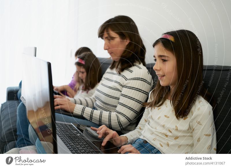 Serious mother and kids spending time together using gadgets on sofa at home children laptop busy addict browsing woman leisure separate sibling parent internet