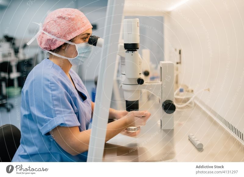 Woman in medical mask examining ovum through microscope woman doctor examine petri dish laboratory clinic inject uniform egg cell embryo modern medicine