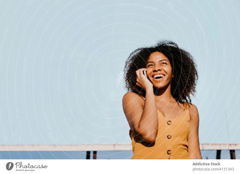 Young satisfied ethnic woman using cellphone on street against empty big board in suburb smartphone billboard use joy banner social media message search watch