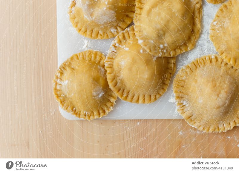 Raw ravioli on table in kitchen cutting board round circle fill pumpkin puree cookery flour raw utensil prepare food italian gastronomy kitchenware bottle tasty