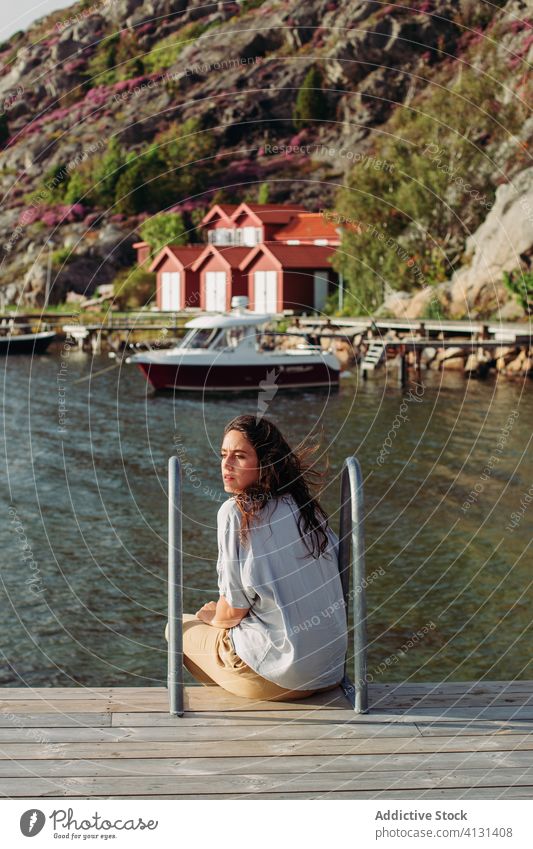 Woman traveler sitting on wooden pier and admiring seascape woman tourist boardwalk relax admire boat calm trip rest peaceful leisure vacation tourism nature