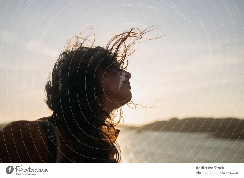 Young woman on embankment near sea breeze enjoy quay sunny seascape young casual female stand calm tranquil serene wind wavy hair relax chill vacation holiday