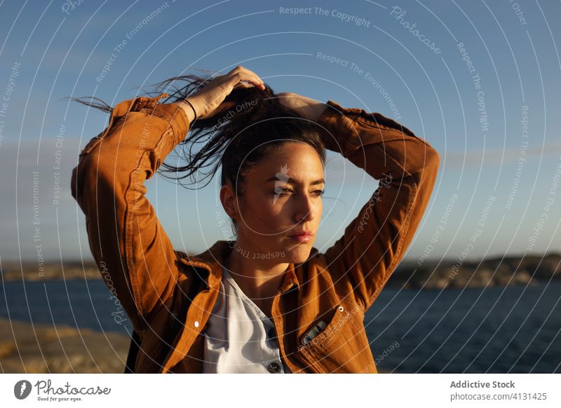 Thoughtful young female tourist standing on rocky seashore and looking away woman traveler harmony dream pensive wave hair wind nature coast vacation thoughtful