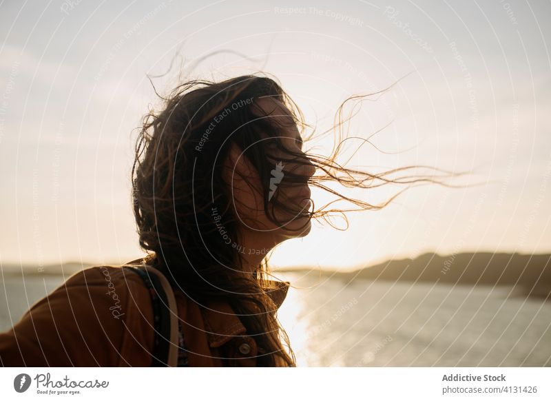 Young woman on embankment near sea breeze enjoy quay sunny seascape young casual female stand calm tranquil serene wind wavy hair relax chill vacation holiday