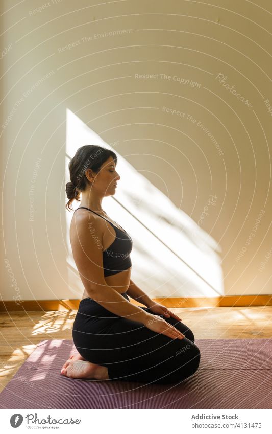 Calm woman sitting on mat in diamond pose at home yoga asana calm meditate sunlight vajrasana slim athlete think peaceful vitality serene daylight focused