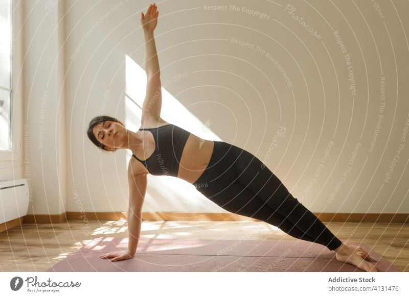 Female practicing side plank on mat at home woman yoga balance asana healthy sport practice eyes closed vasishtasana slim vitality pilates peaceful serene