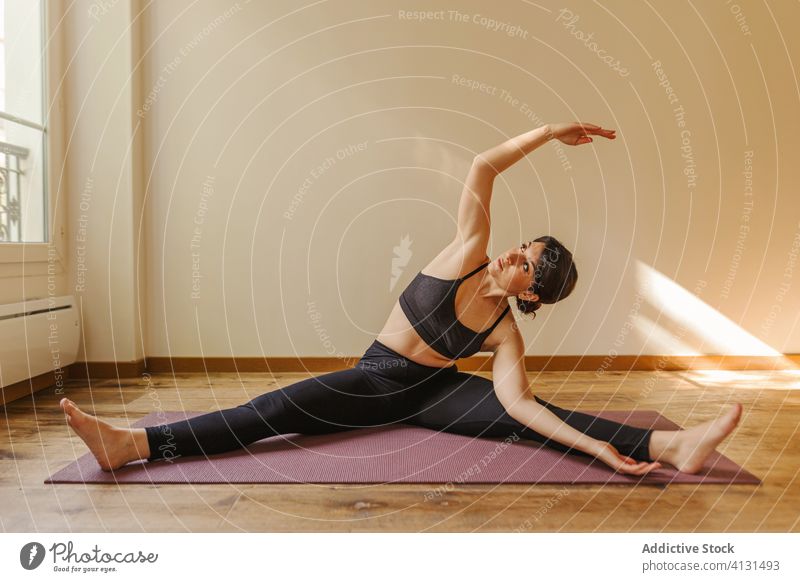 Flexible female sitting in boat pose during yoga workout woman practice stretch vitality touch feet flexible healthy lifestyle mat focused harmony balance