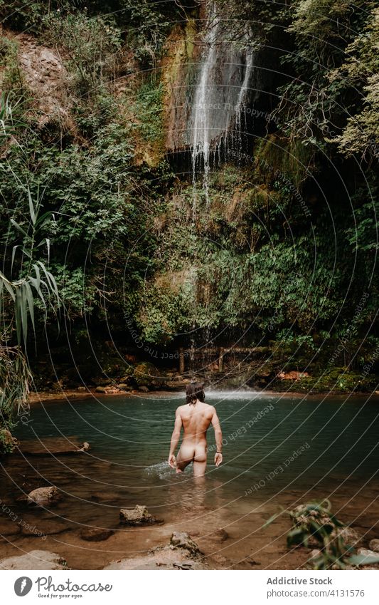 Man taking bath in waterfall pool forest man naked refresh small tropical plant stream jungle male travel tourism nature environment recreation wash nude