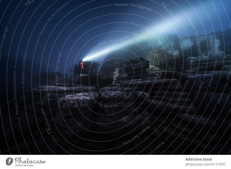 Traveler in headlamp during dark night travel illuminate rock tourist fog rocky cliff nature stone landscape mountain calm tranquil idyllic scenic mist peaceful