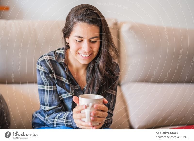 Young woman with cup of coffee resting on sofa home calm pensive young drink female casual cozy couch relax comfort lifestyle beverage sit chill thoughtful