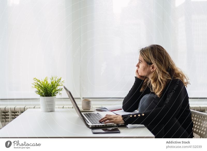 Remote employee working with laptop at home woman using online remote busy casual serious table electronic internet connection read female workplace freelance