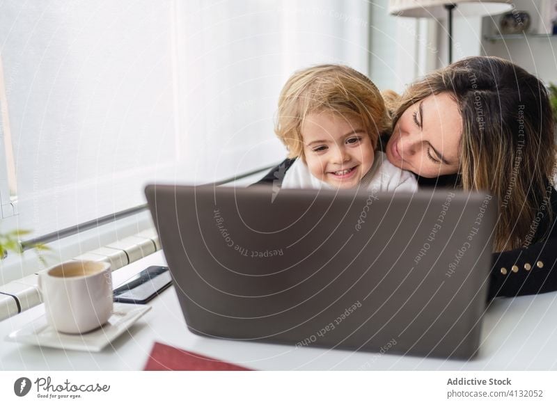 Woman with little kid working on laptop at home woman mother using together online busy remote child curious point motherhood interact parent female