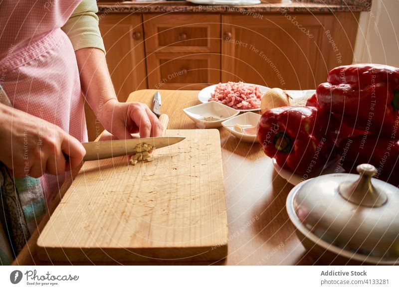 Anonymous woman cooking in kitchen ingredient prepare process cut garlic stuffed peppers female food culinary table fresh healthy vegetable meat sauce recipe