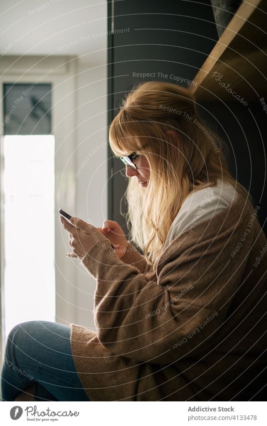 Relaxed woman browsing smartphone relax enjoy morning using female message counter cozy serene sit kitchen social media device home gadget rest read sms