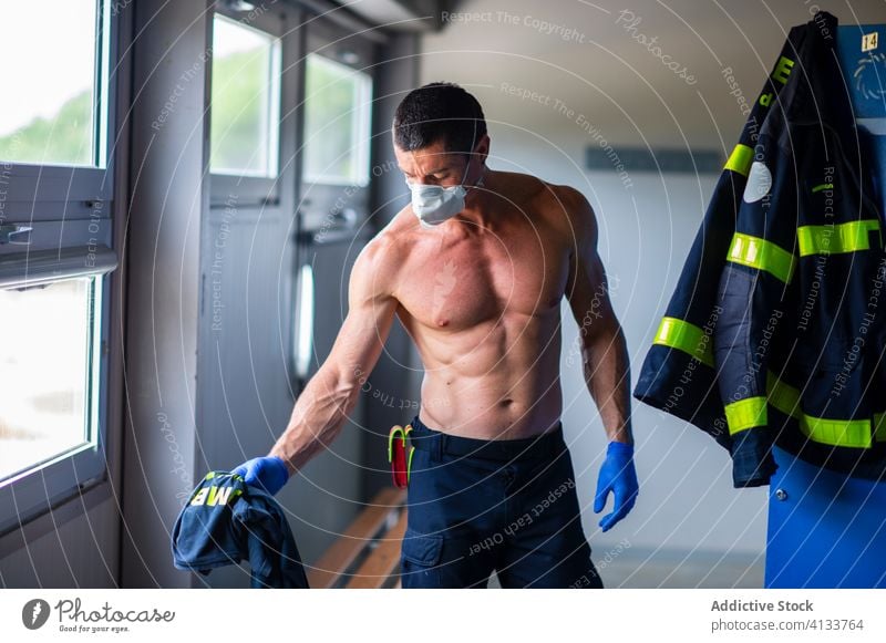 Senior male firefighter at fire station fireman work respirator safety senior strong locker naked torso serious prepare stand muscular face mask professional