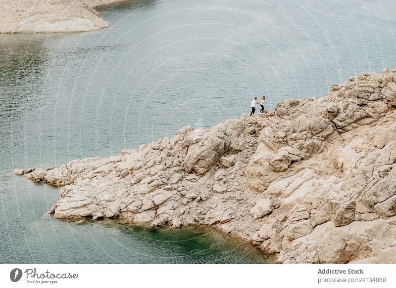 Unrecognizable couple walking on rocky seashore travel coast rough together relationship nature water ocean journey trip love lifestyle landscape seaside ripple