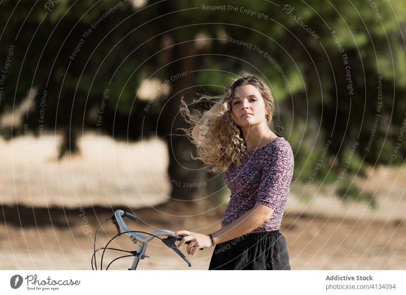 Tranquil woman with bicycle in park bike summer weekend enjoy walk cyclist calm female sunny tranquil serene outfit daytime rest green tree lady carefree