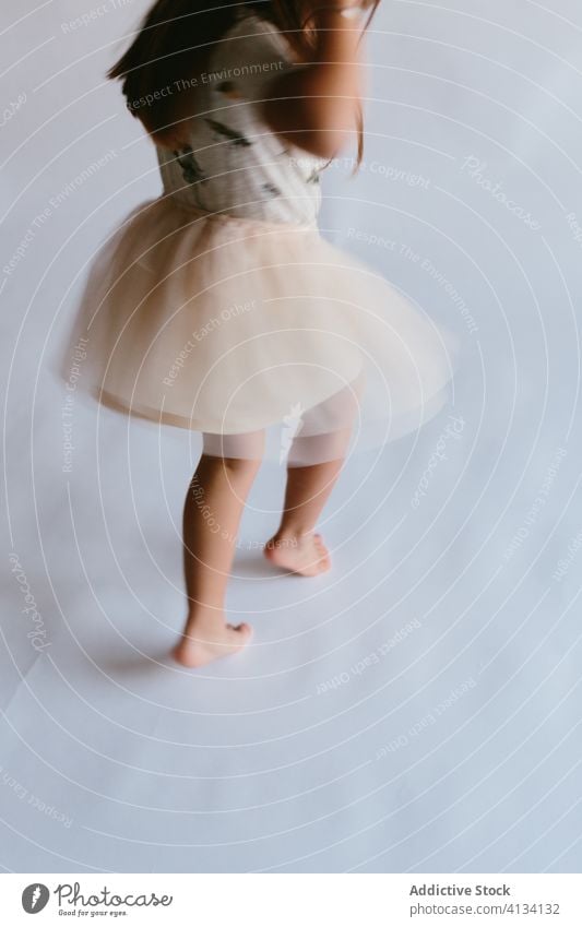 Crop girl in tutu dancing on tiptoes in studio dance having fun child active motion kid playful childhood skirt move barefoot enjoy activity energy perform