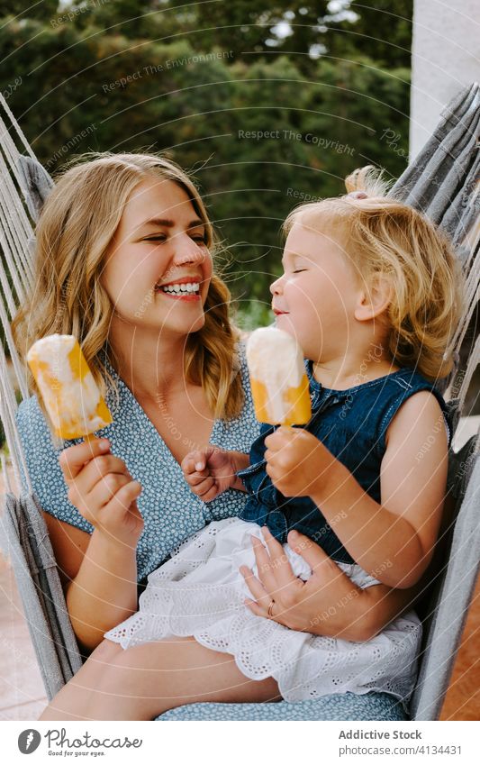 Happy little girl and woman with homemade popsicles mother daughter hug lolly ice enjoy cheerful summer terrace smile ice cream toddler female together