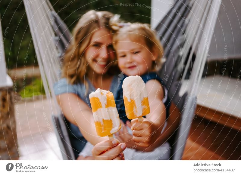 Happy little girl and woman with homemade popsicles mother daughter hug lolly ice enjoy cheerful summer terrace smile ice cream toddler female together