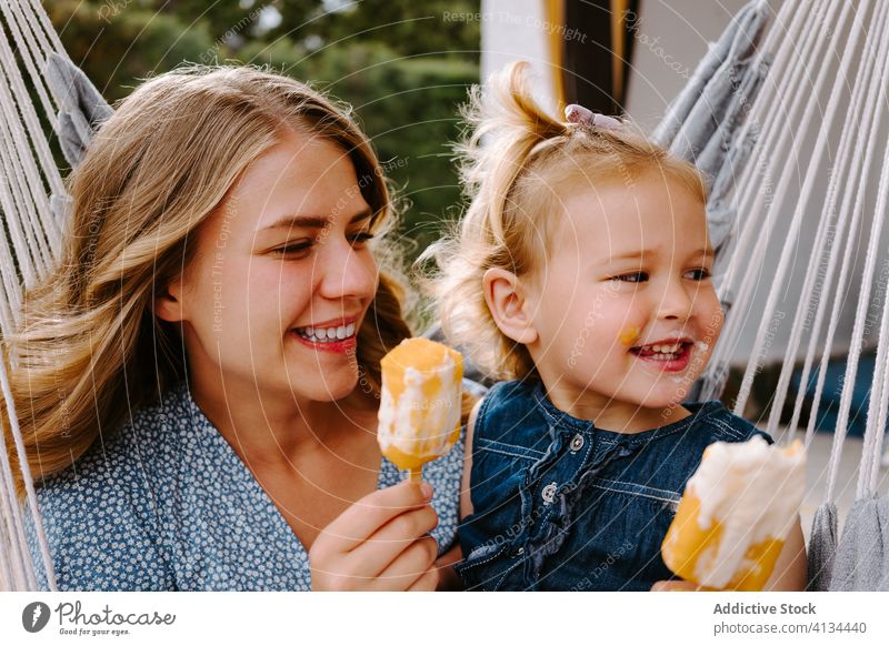 Happy little girl and woman with homemade popsicles mother daughter hug lolly ice enjoy cheerful summer terrace smile ice cream toddler female together