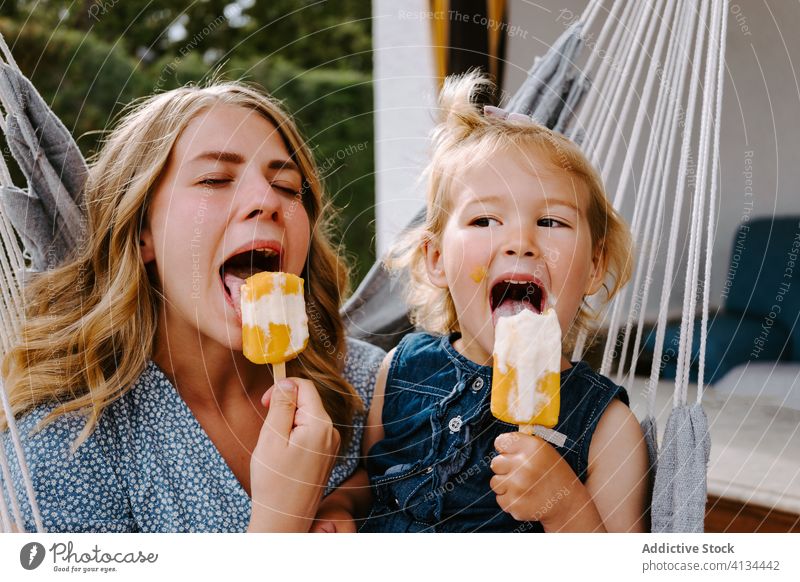 Happy little girl and woman with homemade popsicles mother daughter hug lolly ice enjoy cheerful summer terrace smile ice cream toddler female together