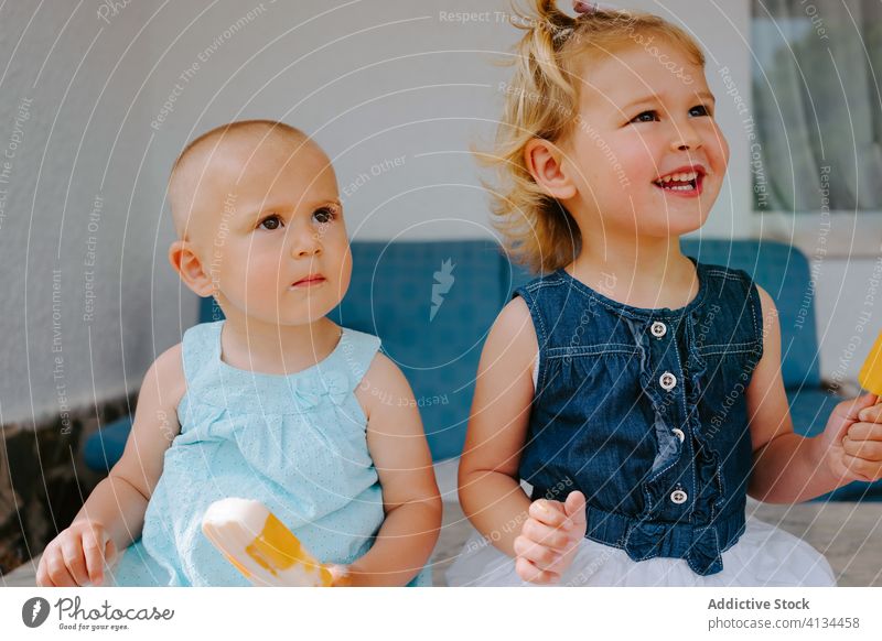 Content sisters eating homemade ice lollies on terrace popsicle lolly girl kid together yummy toddler little delicious sweet cute courtyard tasty dessert