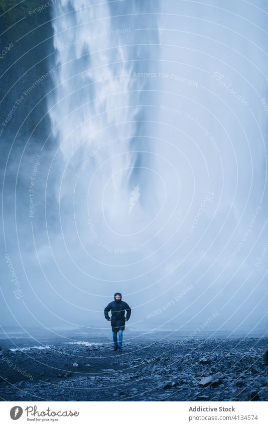 Excited male traveler near powerful waterfall man excited enjoy vacation outerwear cold nature tourism iceland tourist happy adventure walk journey freedom