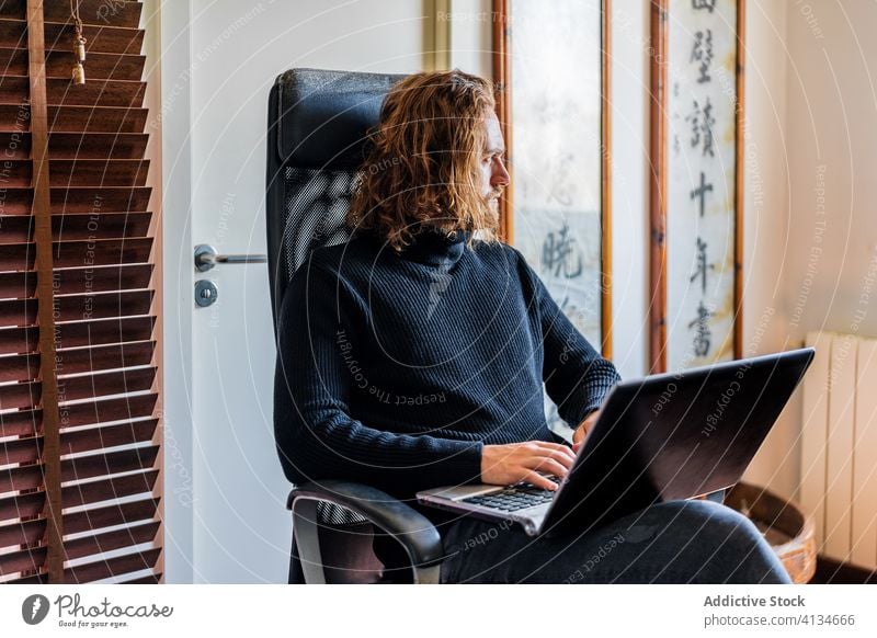 Handsome man working at desktop computer at home typing keyboard freelance remote using male serious project busy gadget device monitor screen watch job