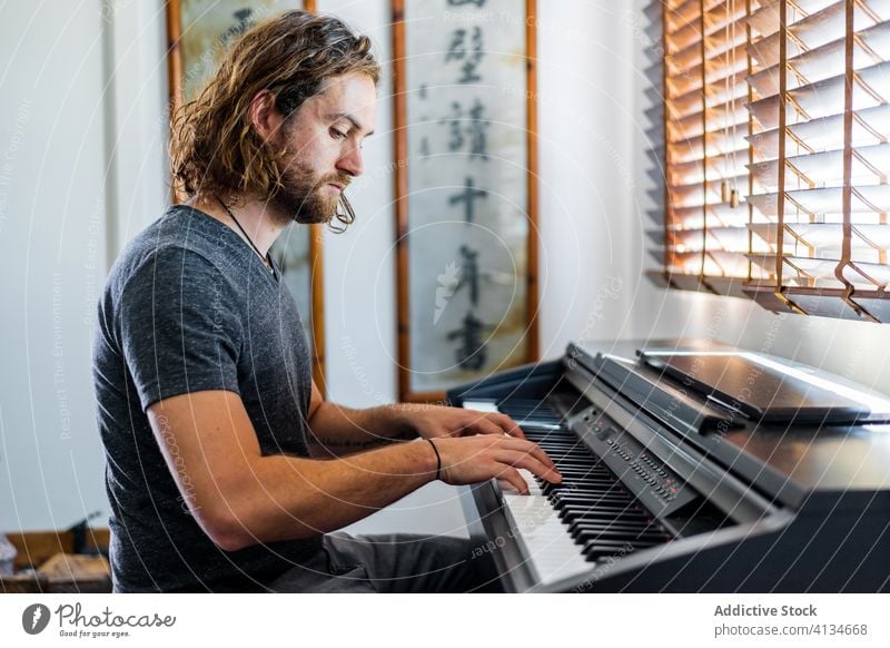 Talented man playing piano at home synthesizer musician instrument electronic talent male skill apartment cozy sit melody sound style entertain modern song guy